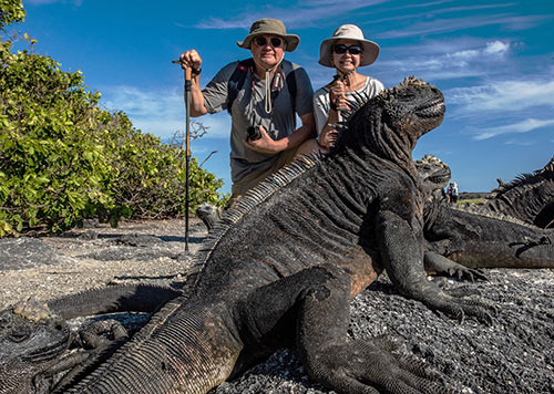 Couple with a marine iguana in the Galapagos Islands
